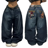 Blue jeans with embroidered designs on the back pocket worn by a person.
