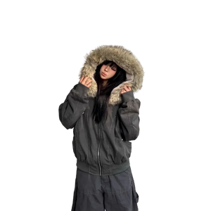 Person wearing a dark gray winter coat with fur-lined hood against a light-colored wall.