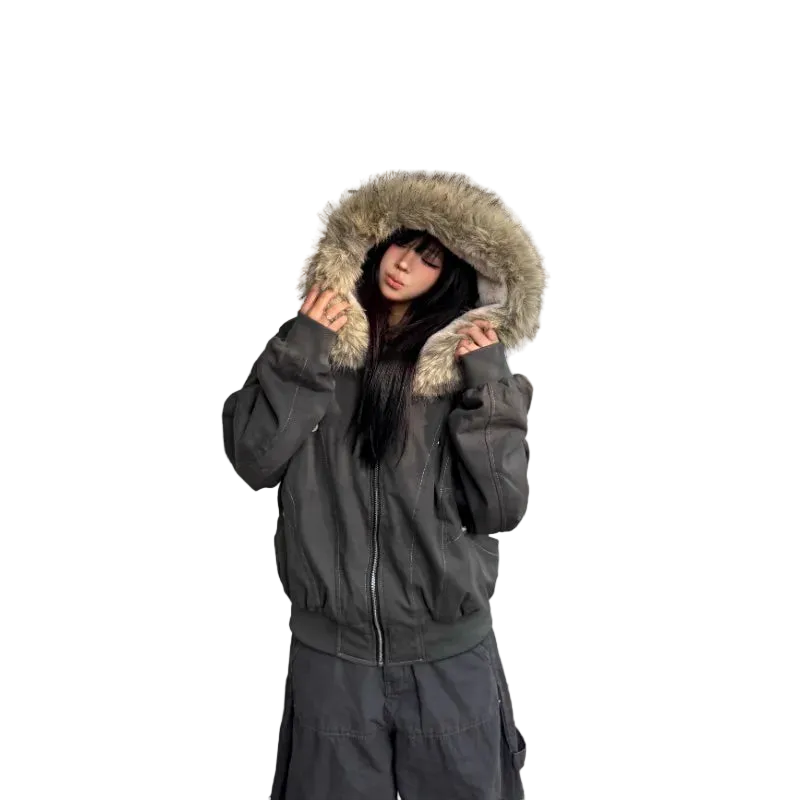 Person wearing a dark gray winter coat with fur-lined hood against a light-colored wall.