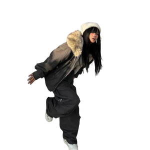 Person wearing a large fur-lined coat and black pants leaning against a building.