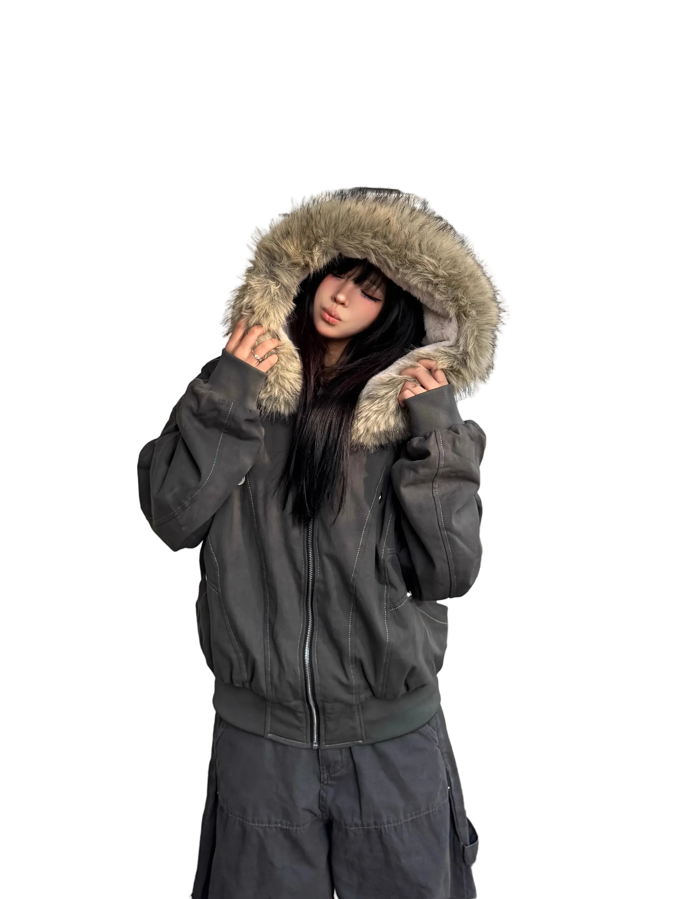 Person wearing a dark gray jacket with a fur-lined hood against a white wall.