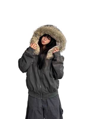 Person wearing a dark gray jacket with a fur-lined hood against a white wall.